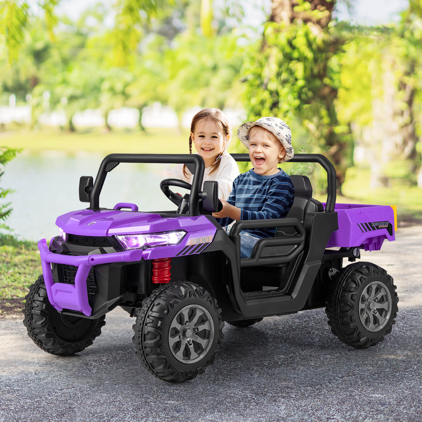 Two children in a purple and black toy off-road vehicle outdoors.