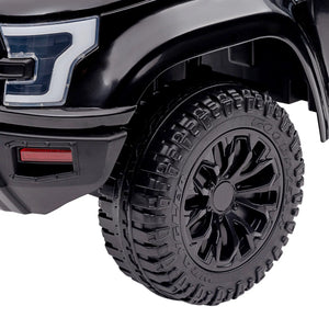 Close-up of a black toy truck with large tire and detailed rim on a white background