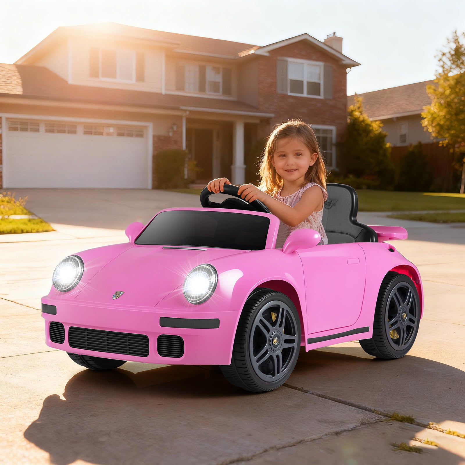 Child in a pink toy car on a driveway with a house in the background