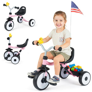Child sitting on a pink tricycle with accessories, including a small American flag and colorful building blocks.