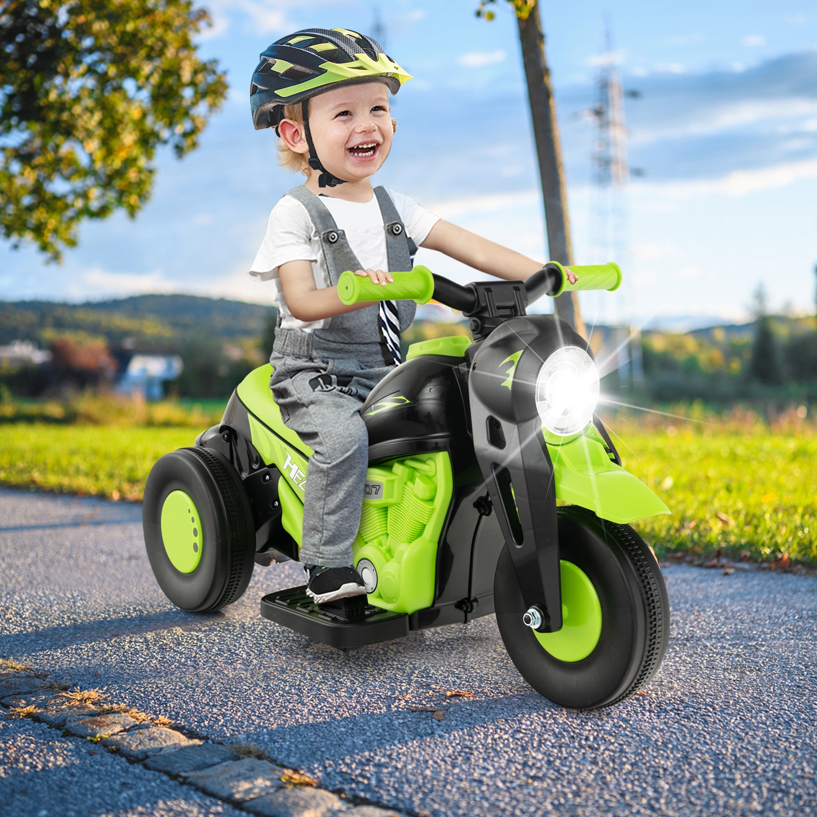 Child riding a green toy motorcycle outdoors on a sunny day