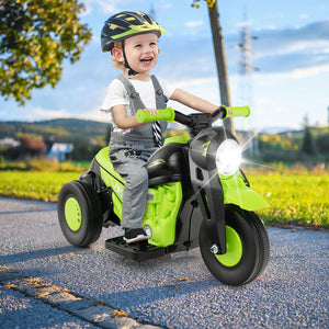Child riding a green toy motorcycle outdoors on a sunny day