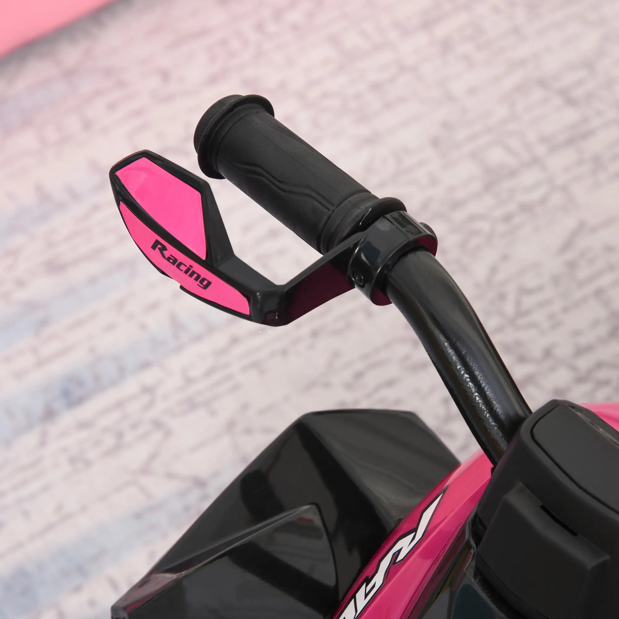 Close-up of pink and black motorcycle handlebar with 'Racing' branding on a textured surface.