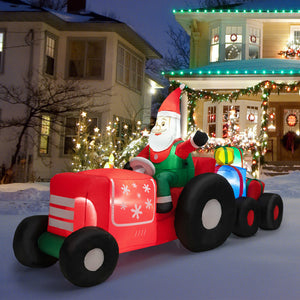 Inflatable Santa Claus on a red truck in front of a decorated house at night.