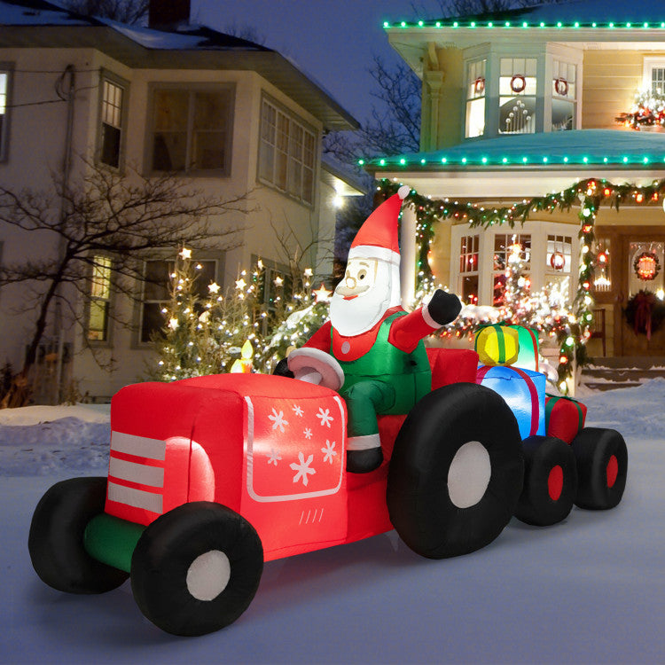 Inflatable Santa Claus on a red truck in front of a decorated house at night.