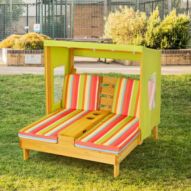 Colorful outdoor playhouse with striped cushions on a grassy area