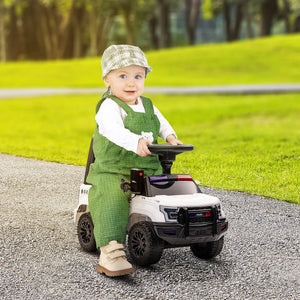 Child in green outfit and cap riding a toy car on a path with grass and trees in the background