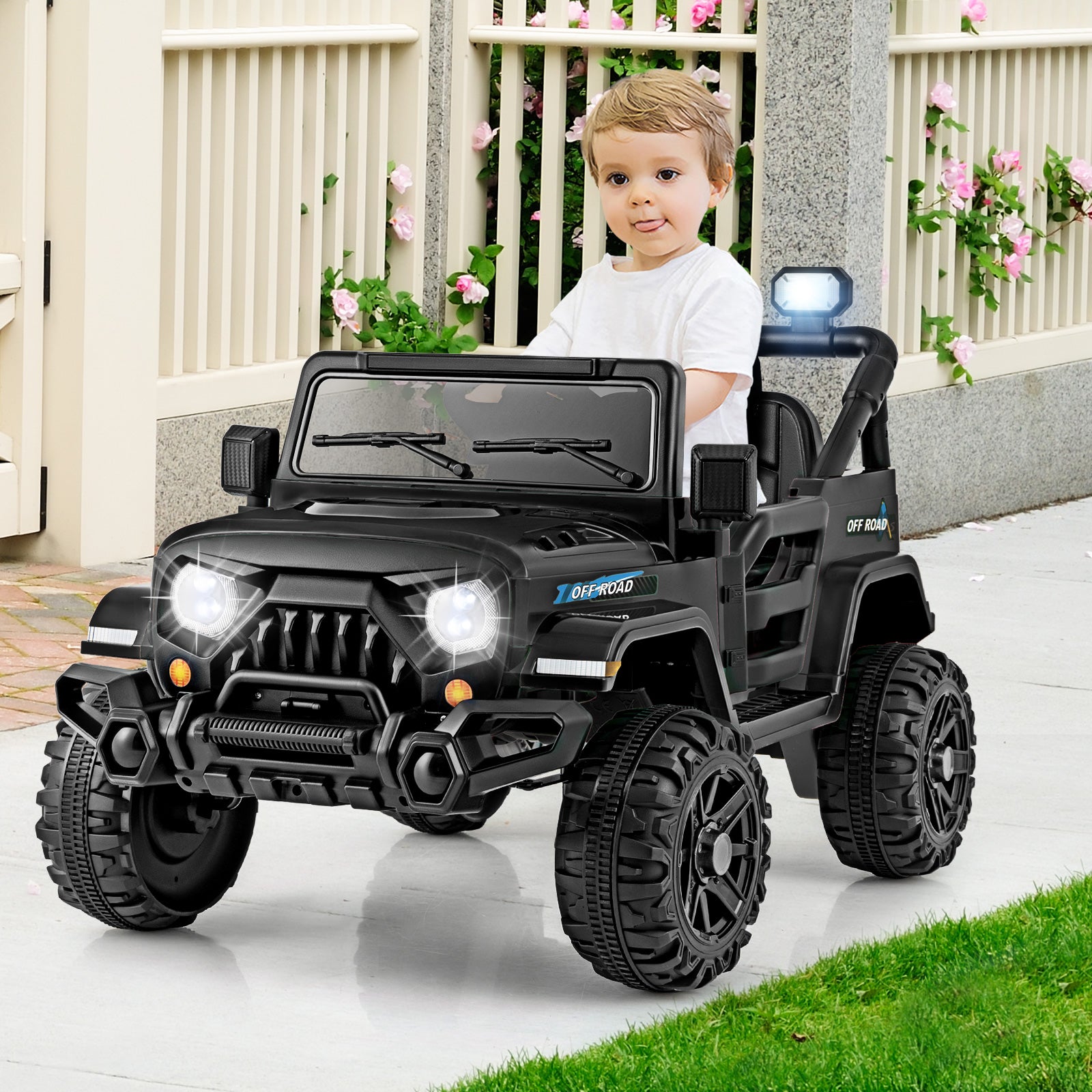 Child playing with a black toy jeep on a patio