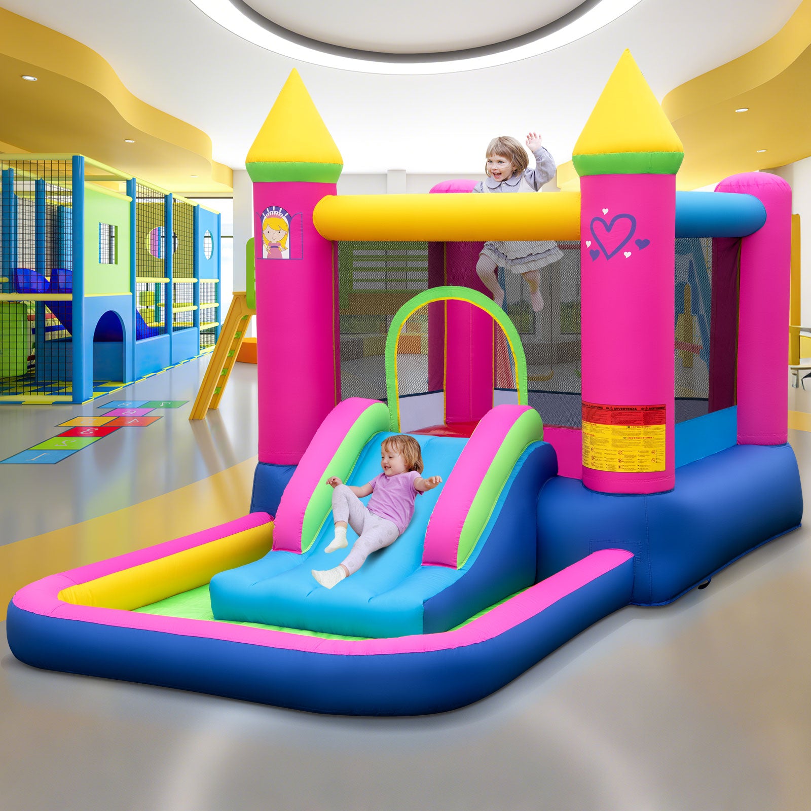 Colorful inflatable playground with slide and castle design in a indoor play area.