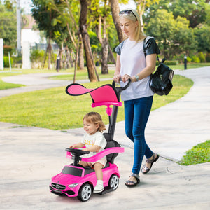 Woman pushing a child in a pink toy car on a sidewalk with trees in the background