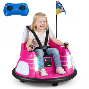 A young child wearing a safety harness sits in a pink and white electric bumper car ride, holding two black joysticks. A blue wireless remote control is shown floating in the upper left, and a small flag is attached to the car.