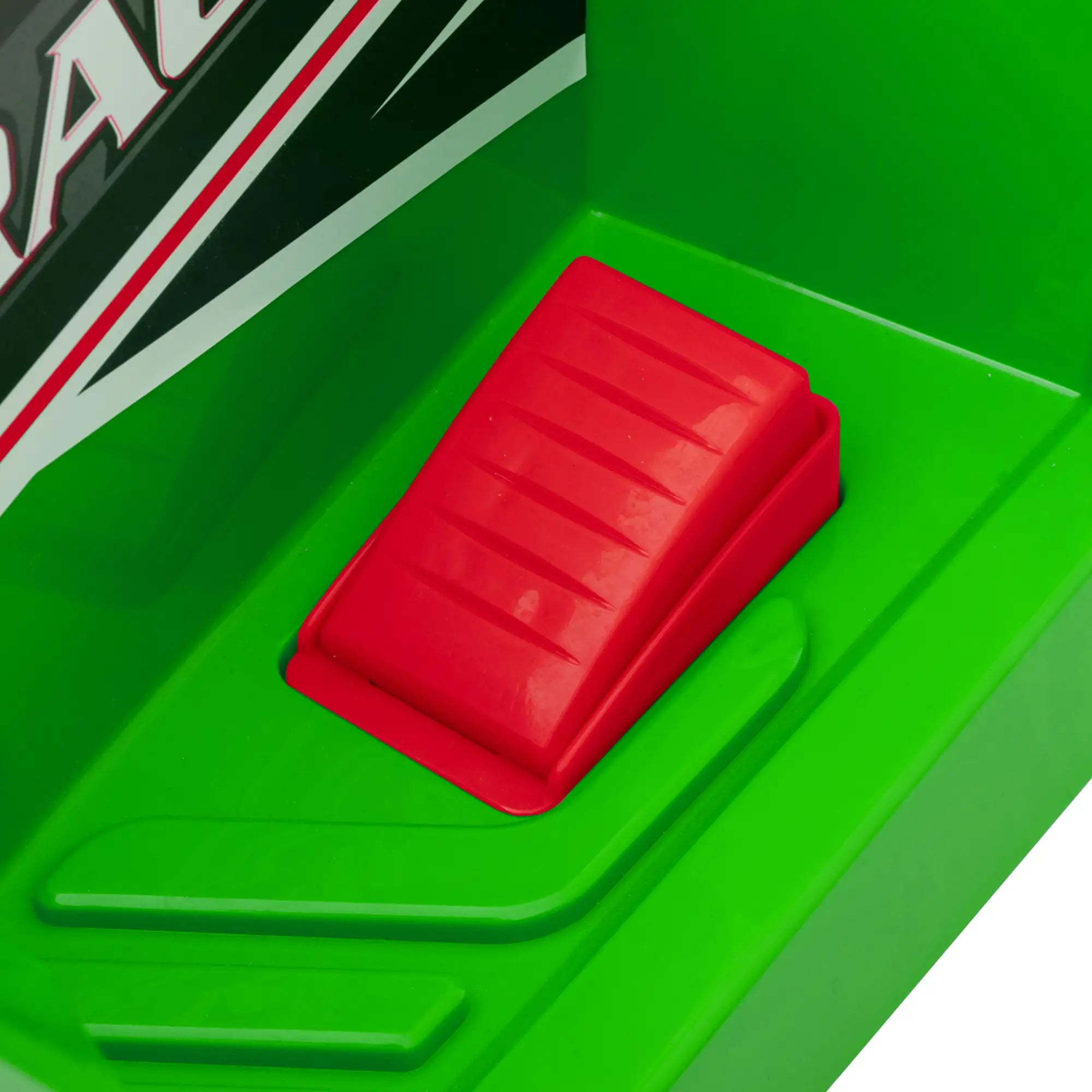Red button on a green surface with a brand logo in the background