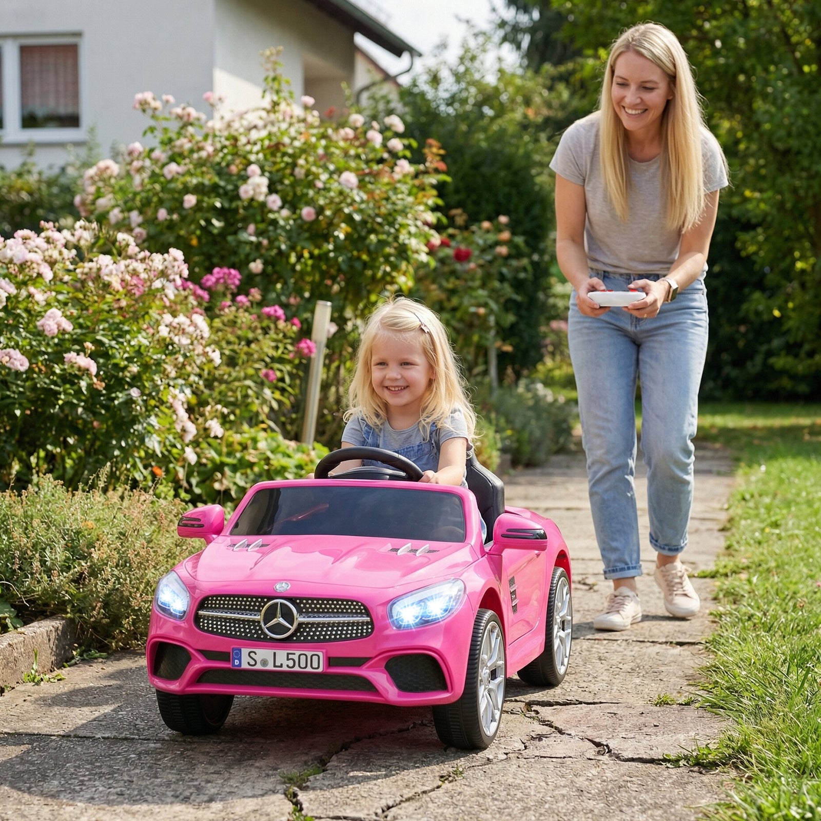 Woman and child playing with a pink toy car in a garden