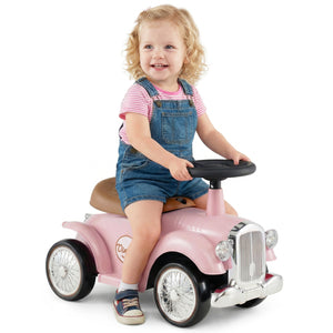 Child sitting on a pink toy car with a white background