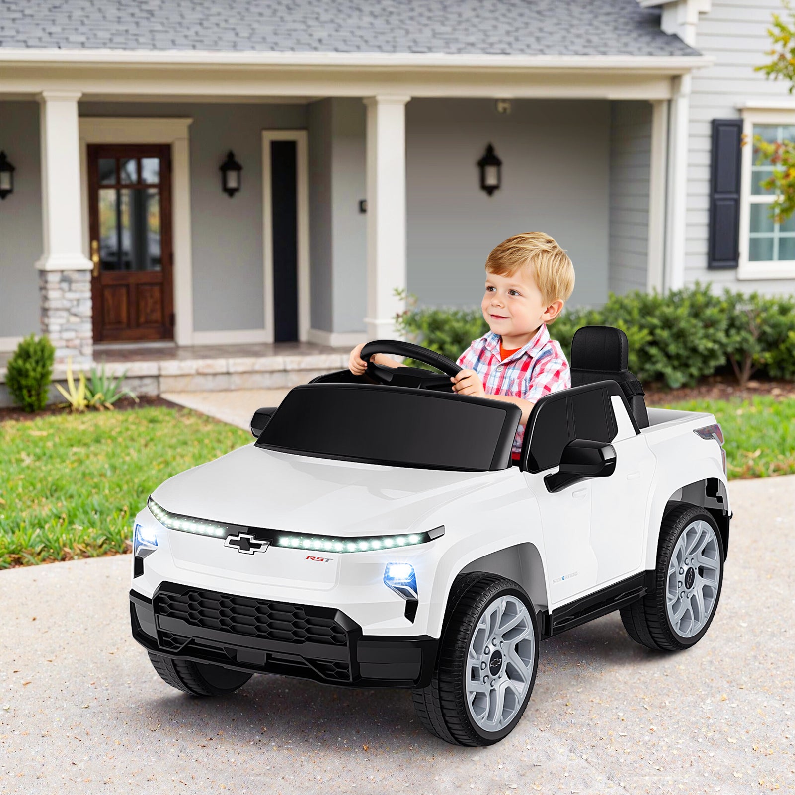 Child driving a white toy car in front of a house