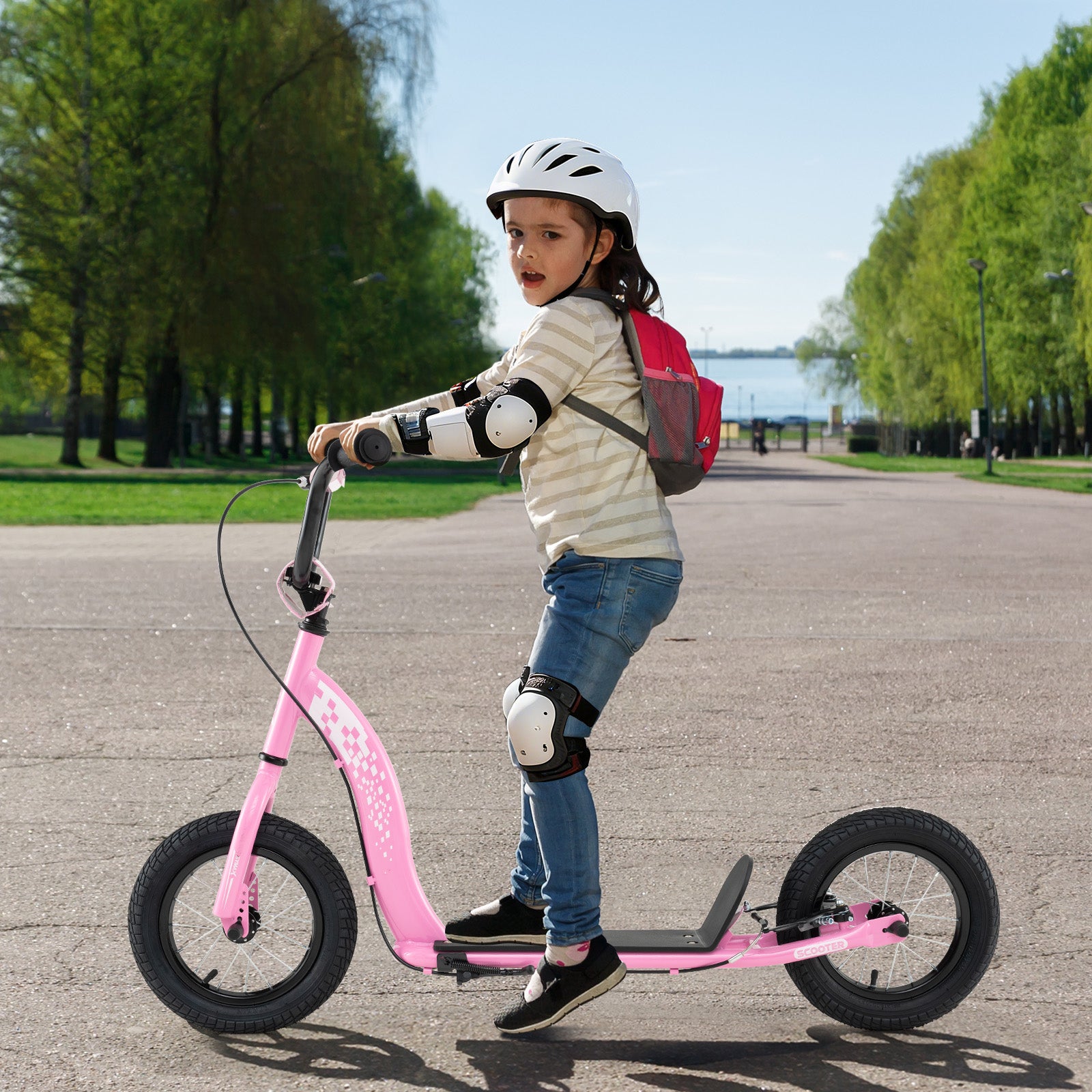 Child riding a pink balance bike on a paved path with trees and water in the background