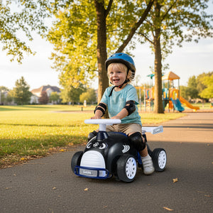 Child riding a toy car in a park with playground equipment in the background