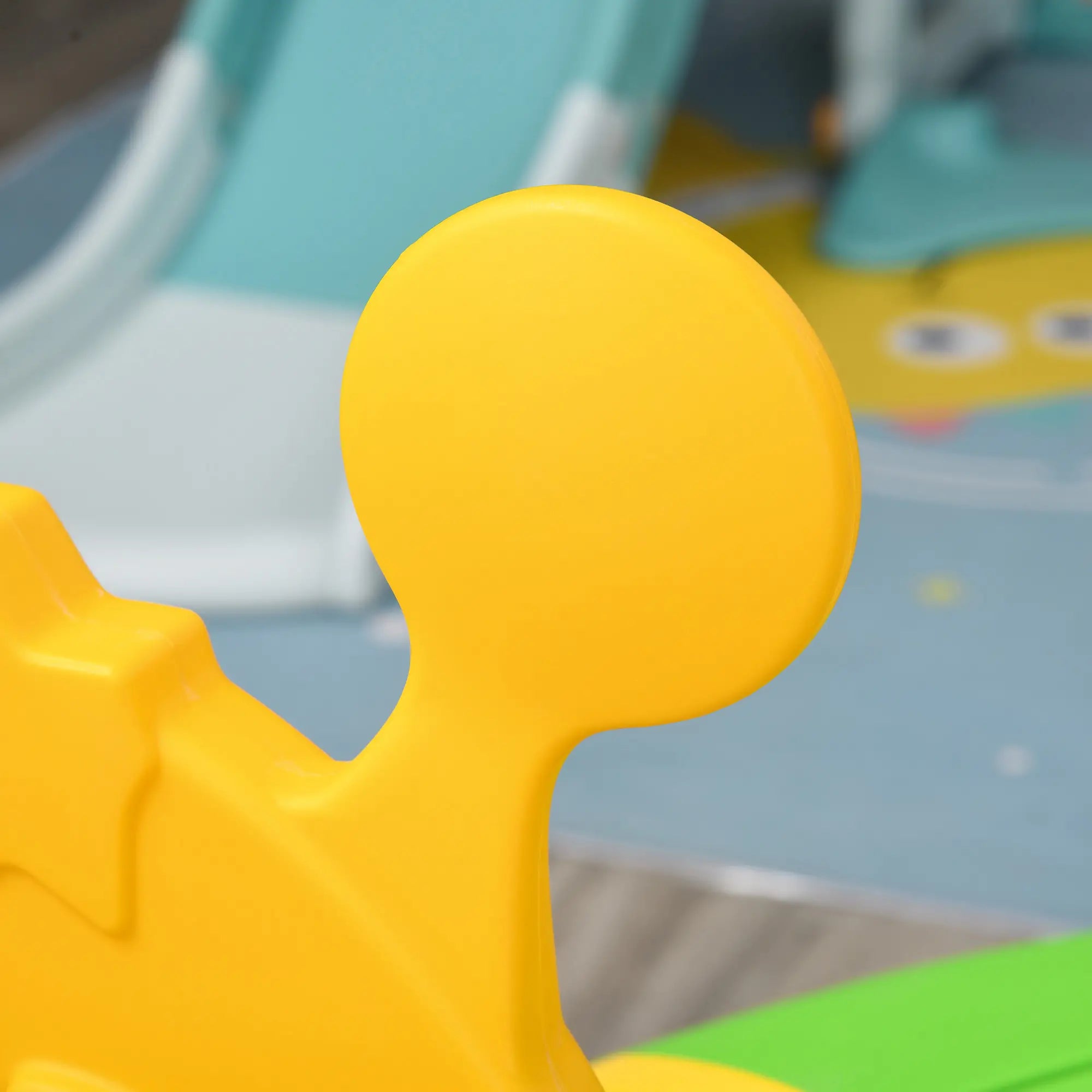 Close-up of a yellow plastic toy figure with a blurred playground background