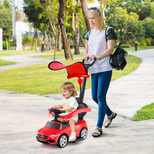 Woman pushing a child in a red toy car on a sidewalk with trees in the background