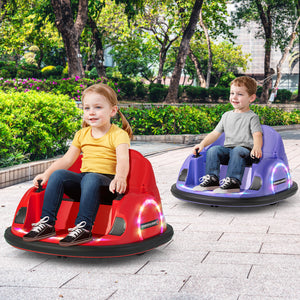 Two children sitting in colorful bumper cars on a paved area with greenery in the background.