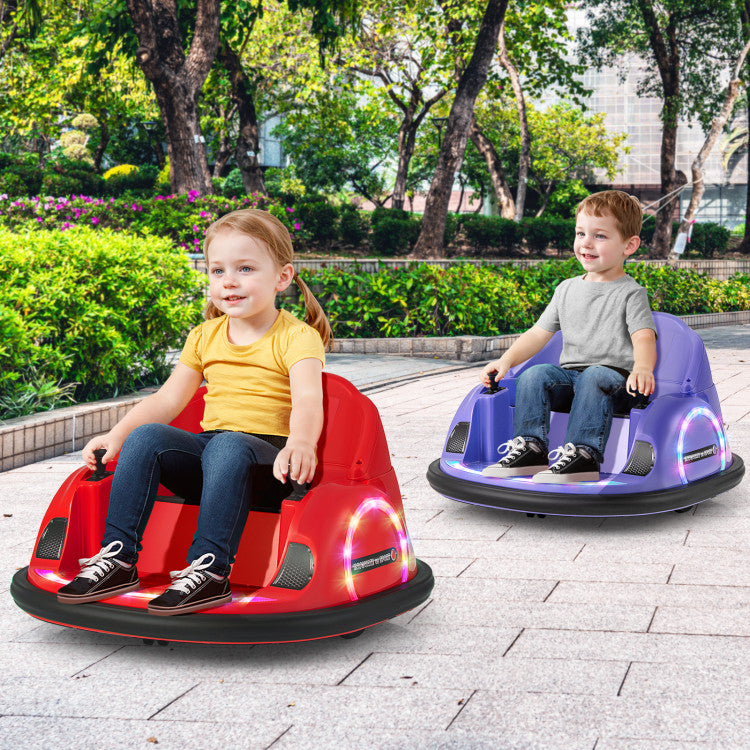 Two children sitting in colorful bumper cars on a paved area with greenery in the background.