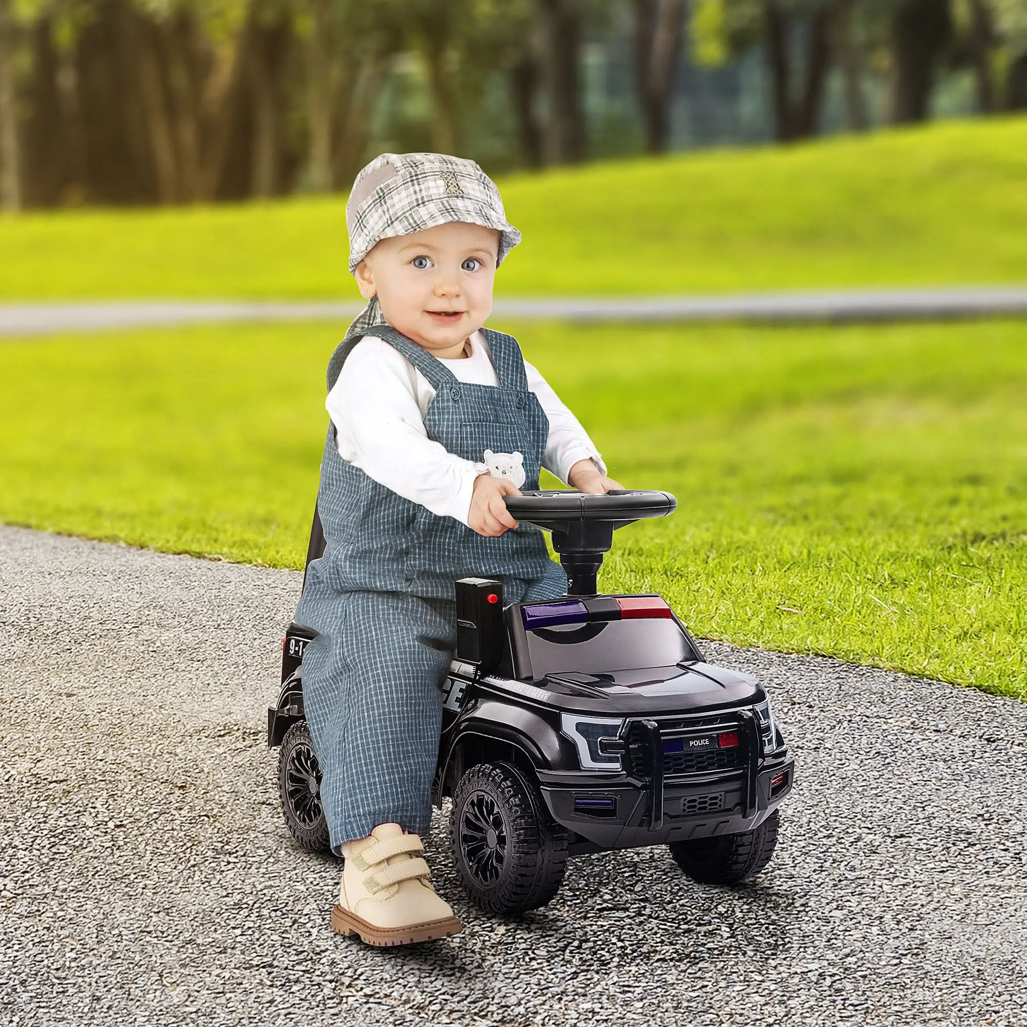 Child sitting on a toy car outdoors with green grass and trees in the background
