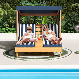Two children sitting on a striped lounge chair by a pool with a tropical background.