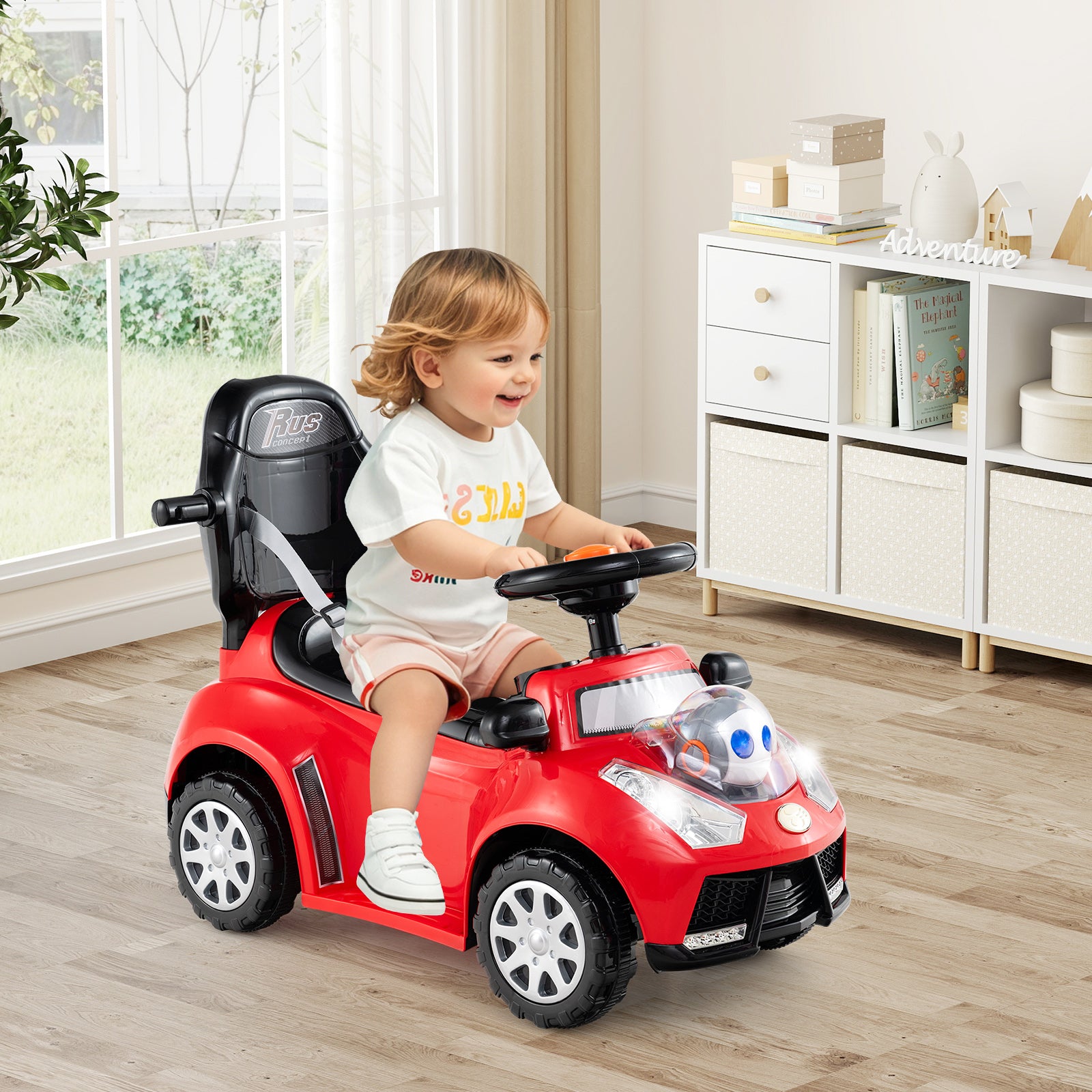Child sitting in a red toy car indoors with a neutral background
