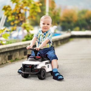 Child sitting on a toy police car outdoors