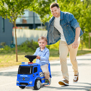 Man pushing a child in a toy police car outdoors