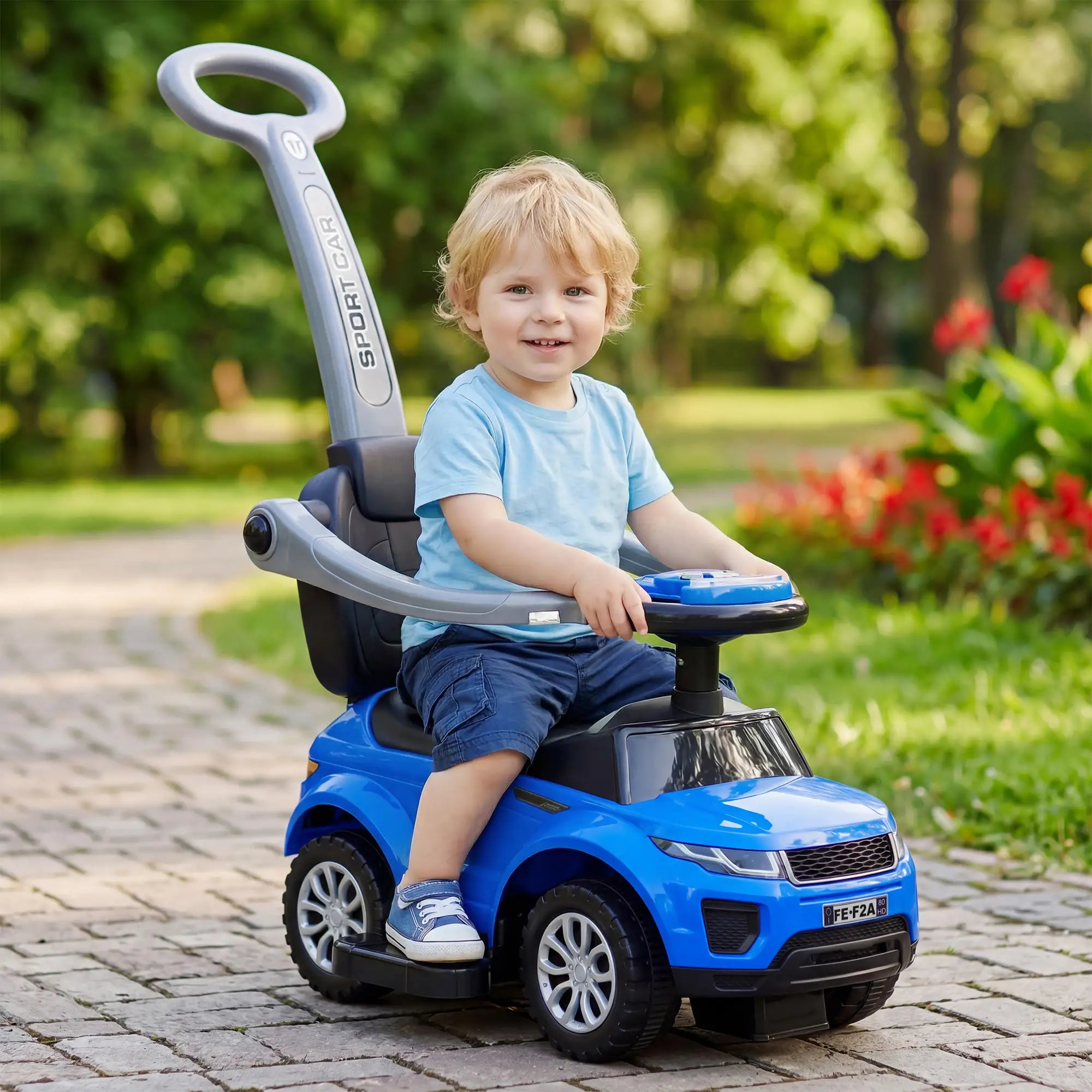 Child sitting in a blue toy car outdoors on a sunny day