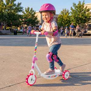 Child riding a scooter with safety gear in an outdoor setting