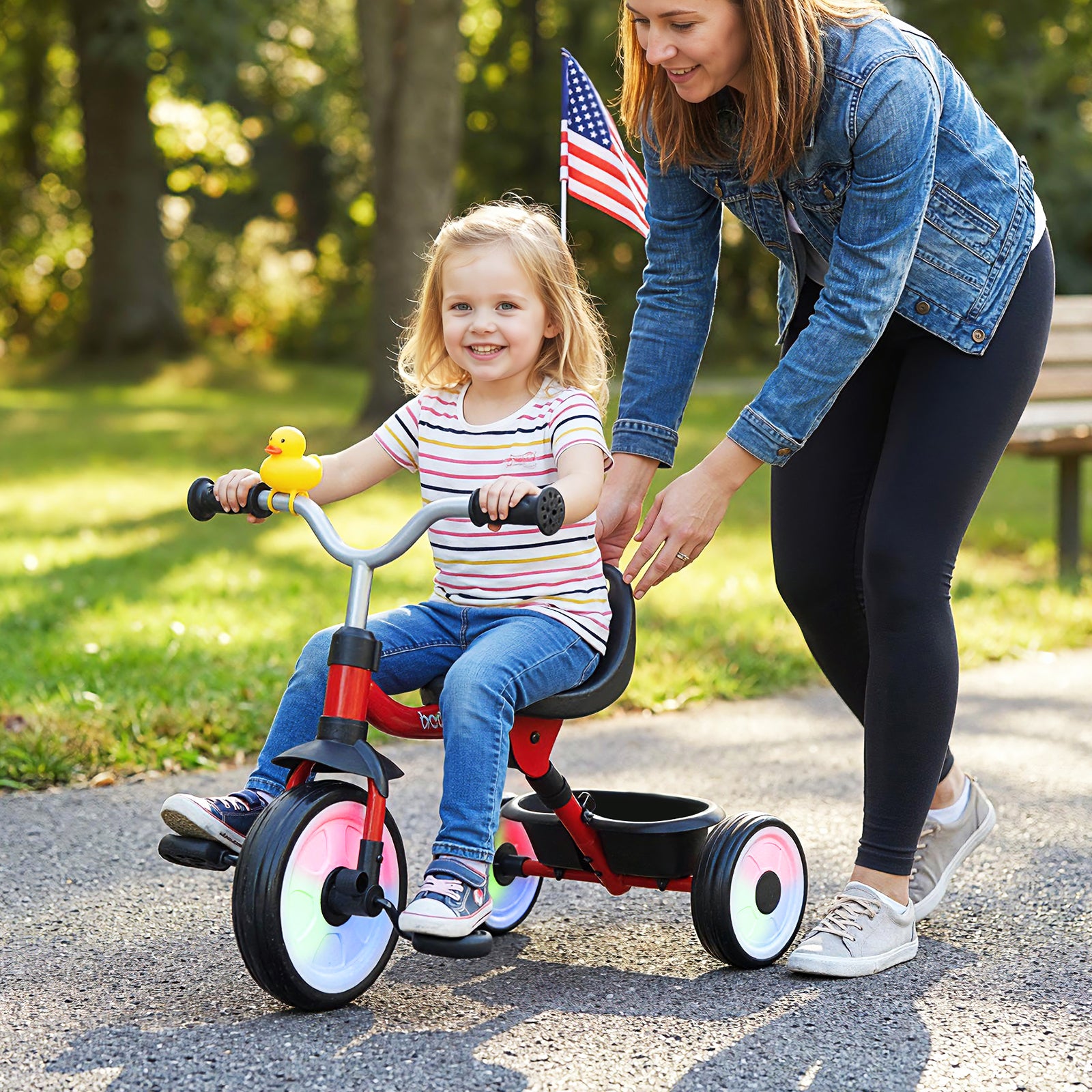 Woman pushing a child on a tricycle in a park