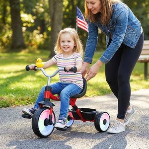 Woman pushing a child on a tricycle in a park