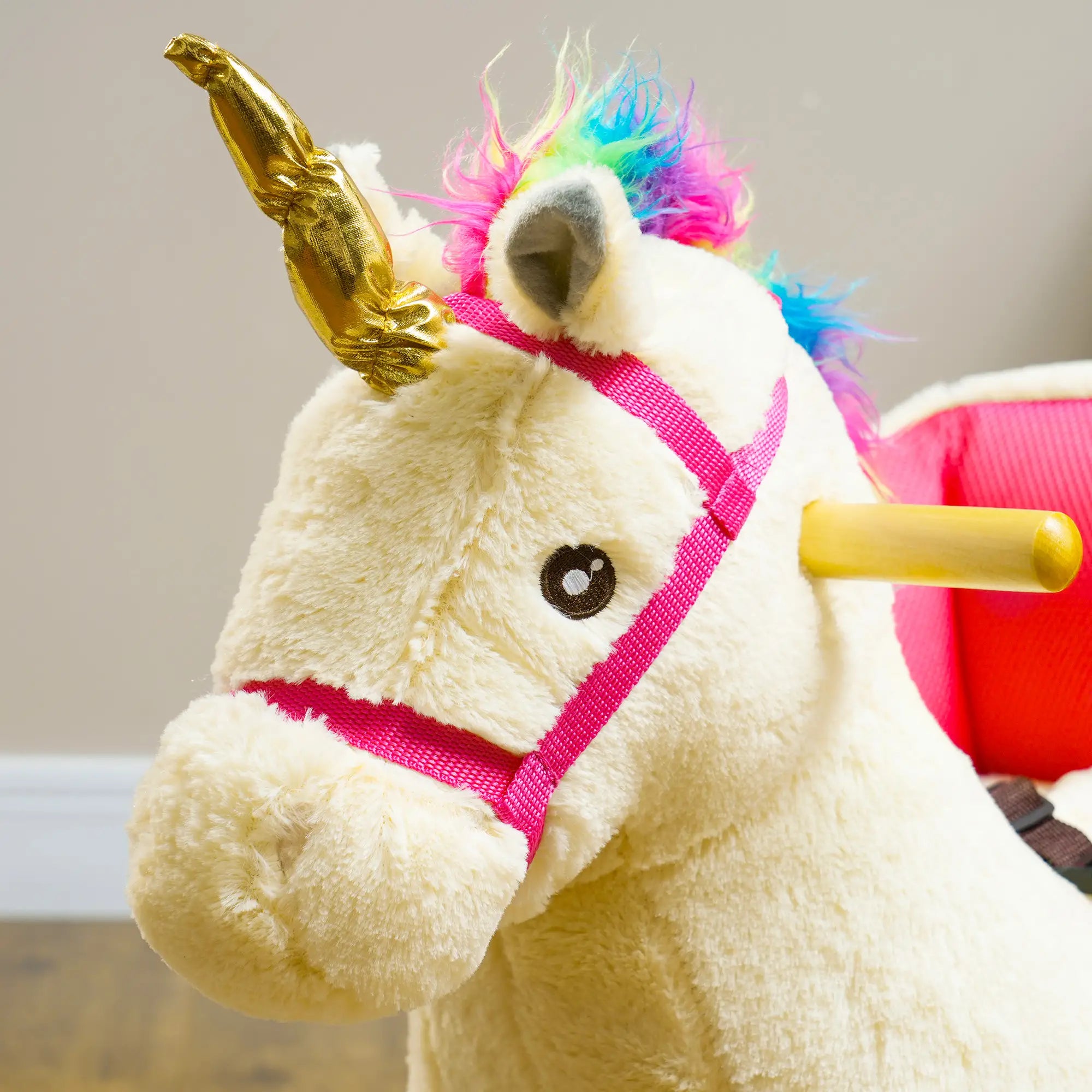 Close-up of a plush unicorn toy with a gold horn and colorful mane.