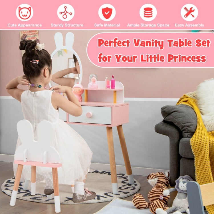 Children's vanity table set with a young girl sitting on a stool, surrounded by toys and furniture.