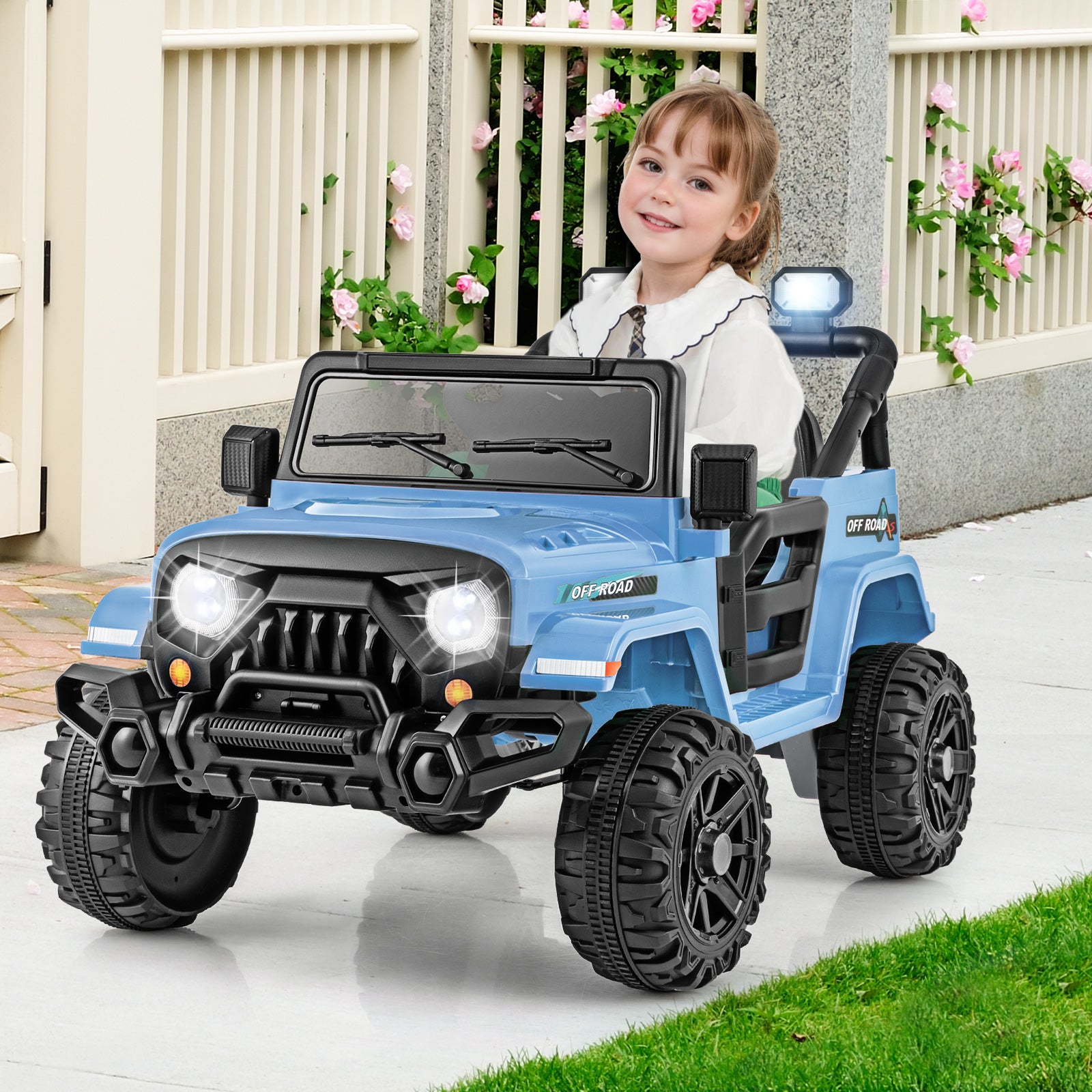Child sitting in a blue toy jeep with a smiling expression, outdoors.